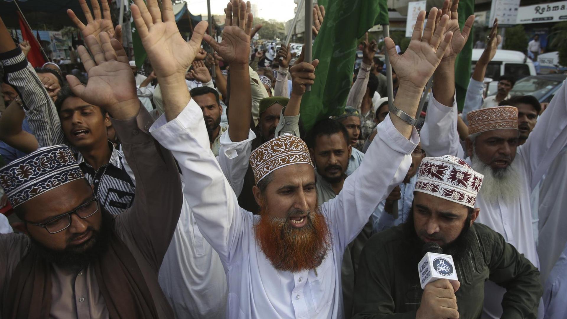 Radikale Islamisten bei einer Demonstration, sie strecken die Hände nach oben.