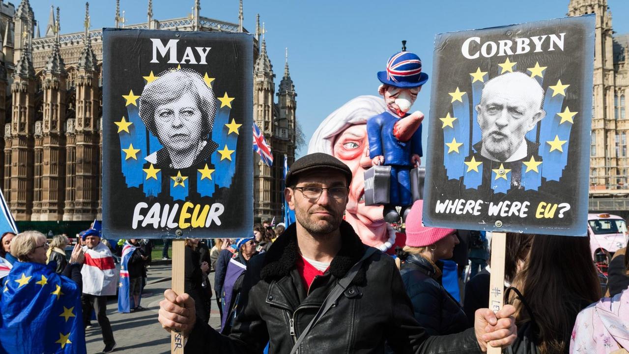 Ein Anti-Brexit-Demonstrant hält Plakate von May und Corbyn in den Händen Ein Anti-Brexit-Demonstrant hält Plakate von May und Corbyn in den Händen