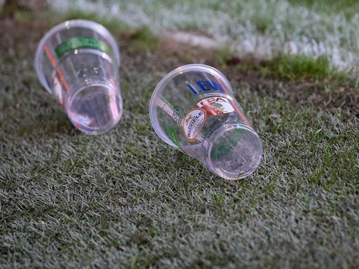 Zwei Becher liegen auf dem Rasen des Stadion in Augsburg.