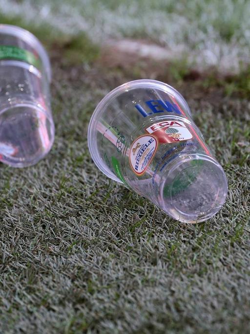 Zwei Becher liegen auf dem Rasen des Stadion in Augsburg.
