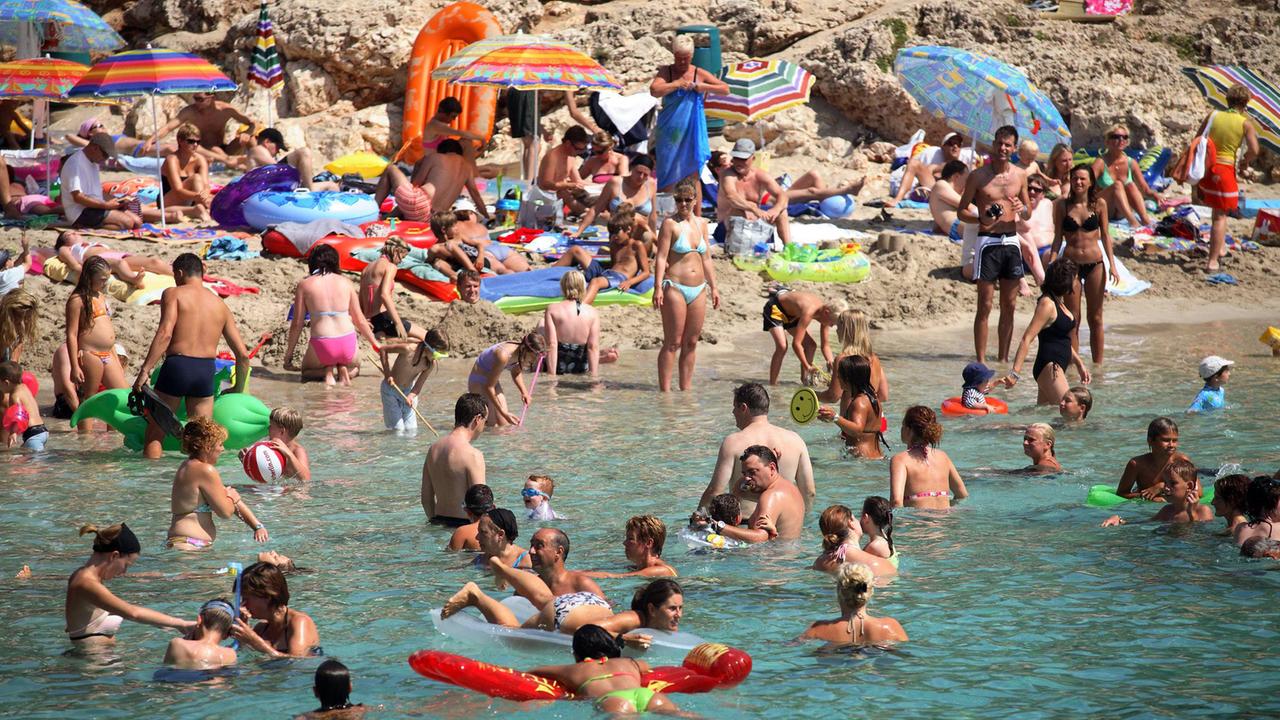 Menschen am Strand von Cala d’Or auf Mallorca.