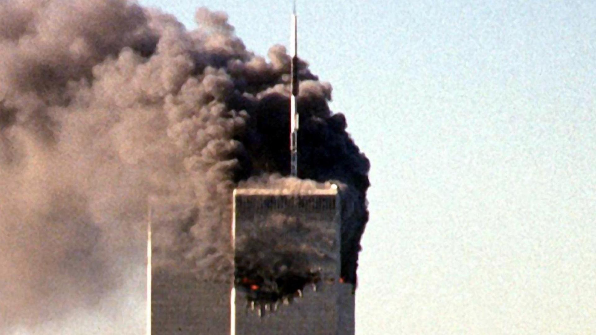 Ein Flugzeug steuert auf den zweiten Turm des World Trade Centers zu. Der erste Turm brennt bereits. 