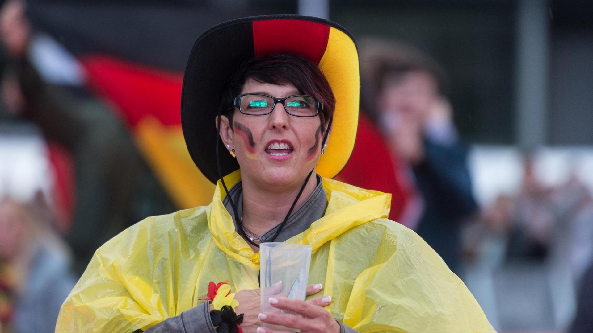Ein deutscher Fußball-Fan singt am 16.06.2016 beim Public Viewing auf dem Messegelände in Freiburg (Baden-Württemberg) im Regen vor der EM-Begegnung Deutschland - Polen die deutsche Nationalhymne. Ein deutscher Fußball-Fan singt am 16.06.2016 beim Public Viewing auf dem Messegelände in Freiburg (Baden-Württemberg) im Regen vor der EM-Begegnung Deutschland - Polen die deutsche Nationalhymne.