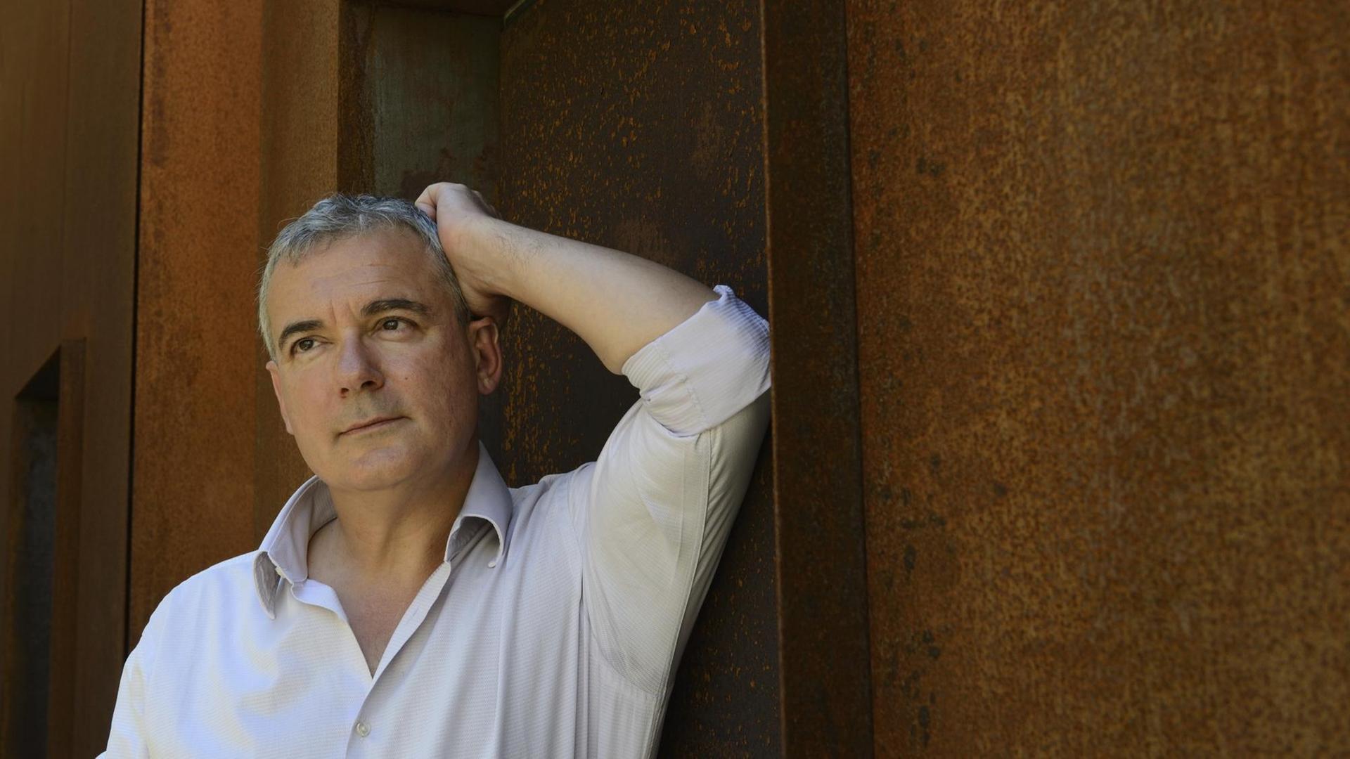 Ilja Trojanow, deutscher Schriftsteller, Uebersetzer, und Verleger. Fotografiert vor einer rost farbenen Hauswand in Erlangen im August 2016. Ilja Trojanow, deutscher Schriftsteller, Uebersetzer, und Verleger. Fotografiert vor einer rost farbenen Hauswand in Erlangen im August 2016.