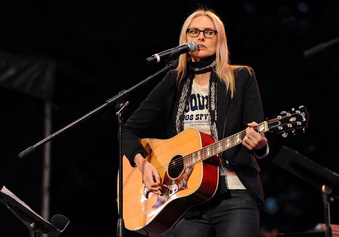 Eine Frau steht auf einer Bühne, spielt Gitarre und singt. Eine Frau steht auf einer Bühne, spielt Gitarre und singt.