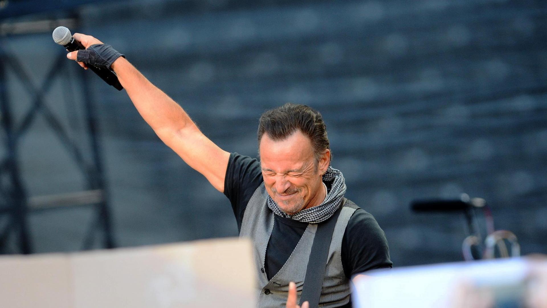 Der US-Rockstar Bruce Springsteen steht auf einer Bühne mit gesclossenen Augen und hält ein Mikrofon Richtung Publikum Der US-Rockstar Bruce Springsteen steht auf einer Bühne mit gesclossenen Augen und hält ein Mikrofon Richtung Publikum