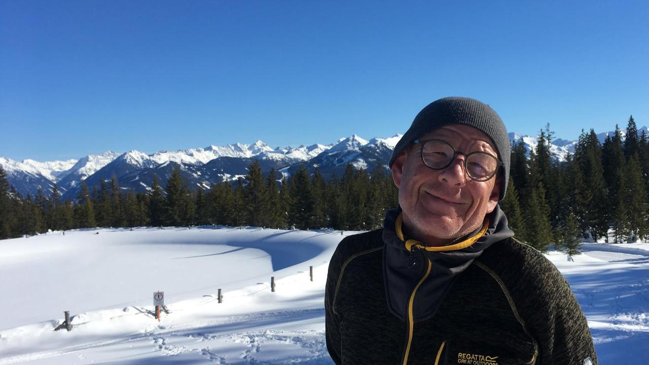 Helmut Krauß steht vor einer schneebedeckten Landschaft und schaut freundlich in die Kamera Helmut Krauß steht vor einer schneebedeckten Landschaft und schaut freundlich in die Kamera