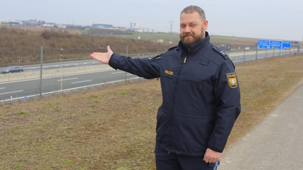 Ein Mann in Polizeiuniform steht an einer Autobahn. Ein Mann in Polizeiuniform steht an einer Autobahn.