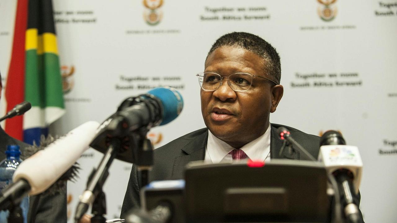 Der südafrikanische Sportminister Fikile Mbalula spricht auf einer Pressekonferenz in Mikrofone, hinter ihm die Flagge des Landes. Der südafrikanische Sportminister Fikile Mbalula spricht auf einer Pressekonferenz in Mikrofone, hinter ihm die Flagge des Landes.