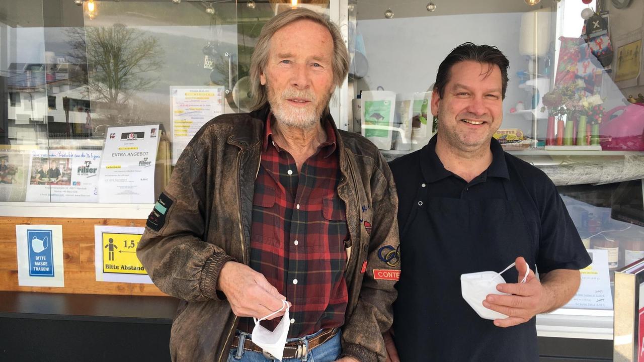 Horst Janson und Christian Loisl stehen vor Loisl Imbisswagen und schauen in die Kamera. Horst Janson und Christian Loisl stehen vor Loisl Imbisswagen und schauen in die Kamera.