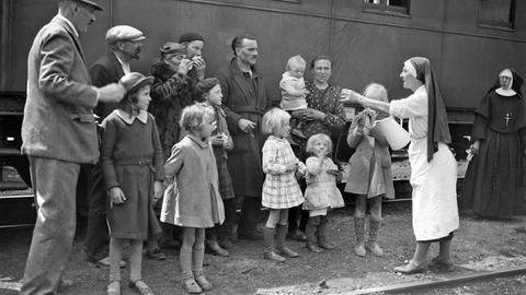 Eine Krankenschwester verteilt während des Zweiten Weltkriegs in einem französischen Bahnhof im Mai 1940 Wasser an Flüchtlingsfamilien.