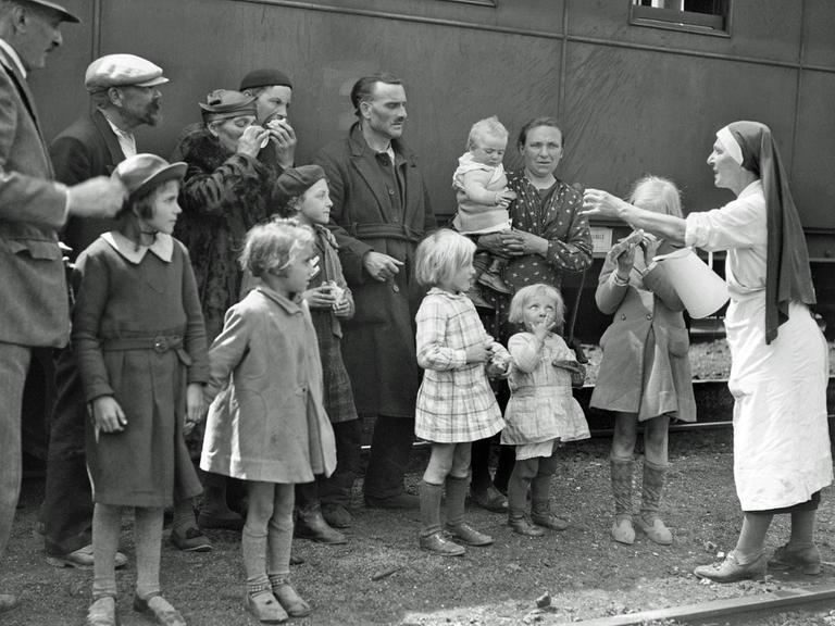 Eine Krankenschwester verteilt während des Zweiten Weltkriegs in einem französischen Bahnhof im Mai 1940 Wasser an Flüchtlingsfamilien.