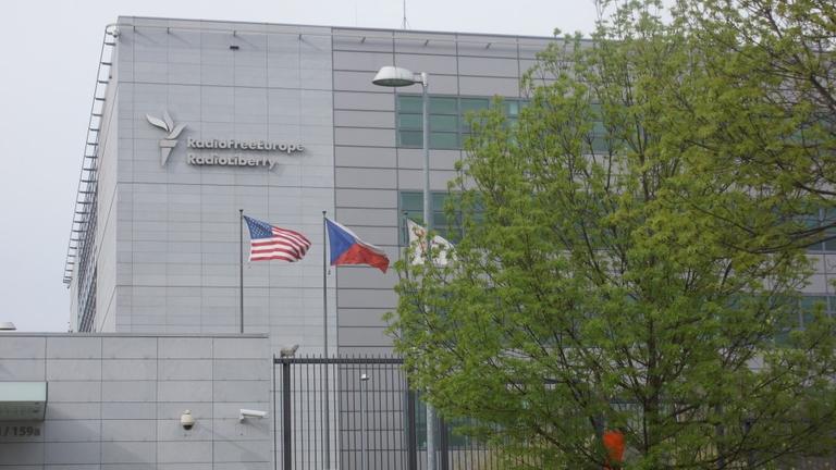 Die Redaktion von RadioFreeEurope in Prag befindet sich in einem Hochsicherheitsgebäude hinter hohen Zäunen , dahinter wehen Landesflaggen, Überwachungskameras sind an den Wänden angebracht Die Redaktion von RadioFreeEurope in Prag befindet sich in einem Hochsicherheitsgebäude hinter hohen Zäunen , dahinter wehen Landesflaggen, Überwachungskameras sind an den Wänden angebracht