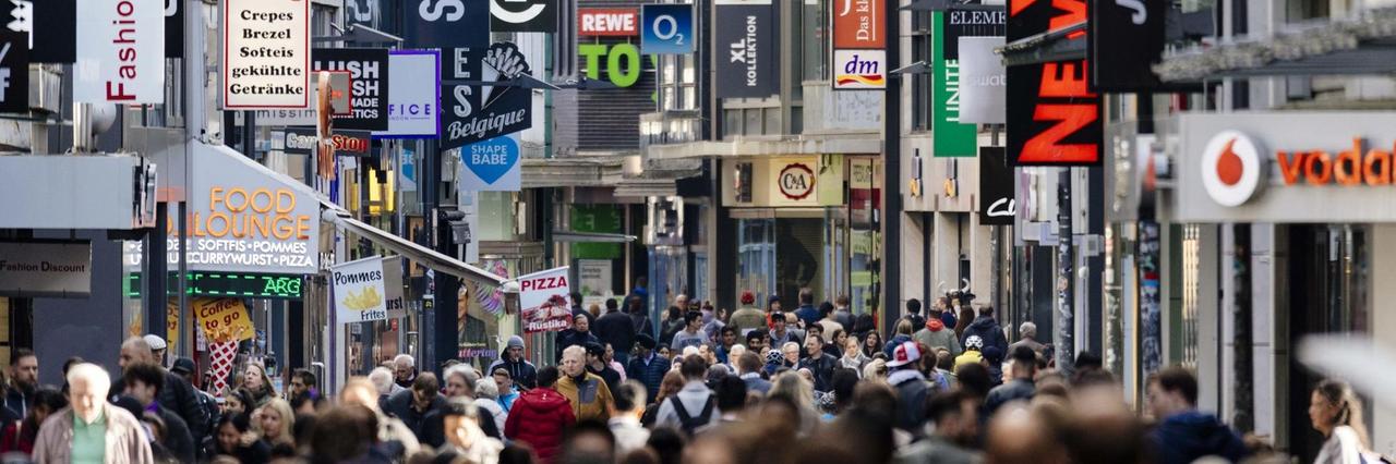 Passanten auf der Hohe Straße in Köln, im Hintergrund sind die Schilder vieler Geschäfte zu sehen, aufgenommen im Mai 2018. Passanten auf der Hohe Straße in Köln, im Hintergrund sind die Schilder vieler Geschäfte zu sehen, aufgenommen im Mai 2018.