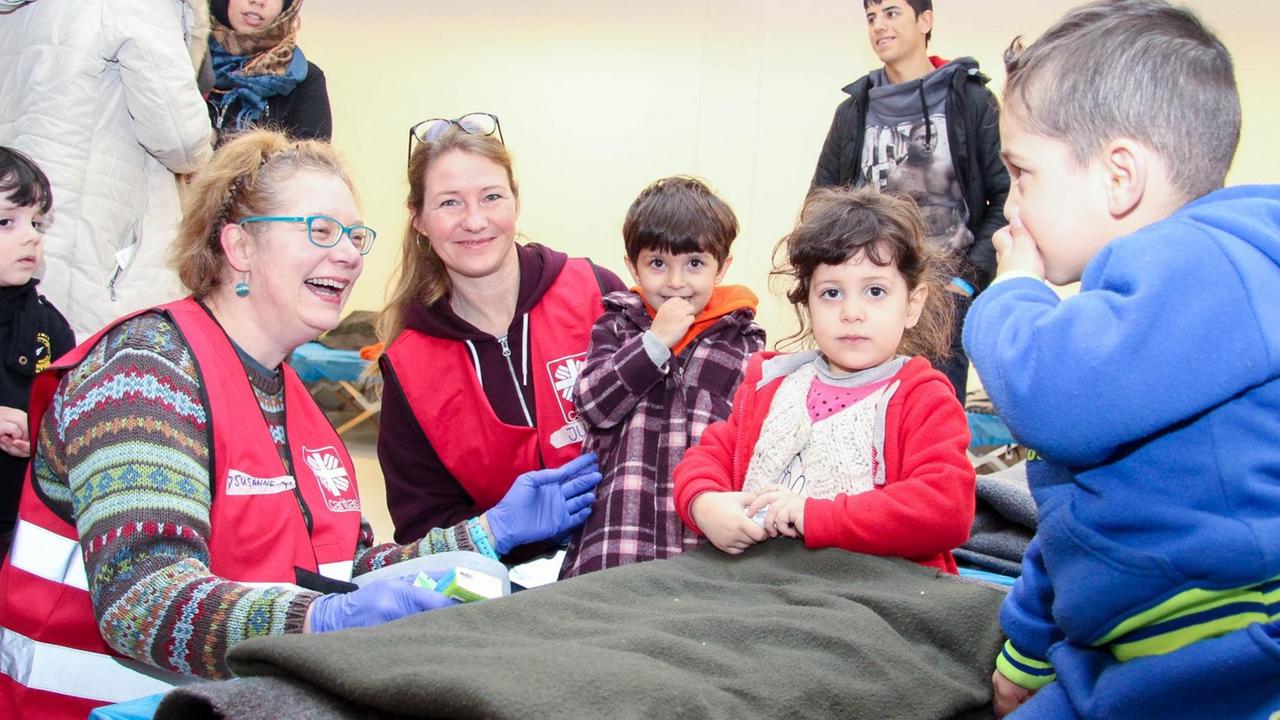 Man sieht zwei Frauen und einige Flüchtlingskinder. Alle sehen fröhlich aus. Man sieht zwei Frauen und einige Flüchtlingskinder. Alle sehen fröhlich aus.