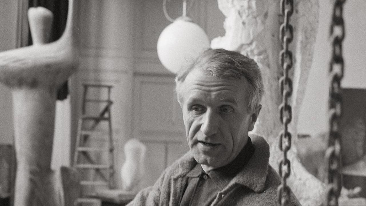 Eine schwarzweiß Fotogrfie zeigt den Bildhauer Bernd Heiliger vor Skulpturen in seinem Atelier. Eine schwarzweiß Fotogrfie zeigt den Bildhauer Bernd Heiliger vor Skulpturen in seinem Atelier.