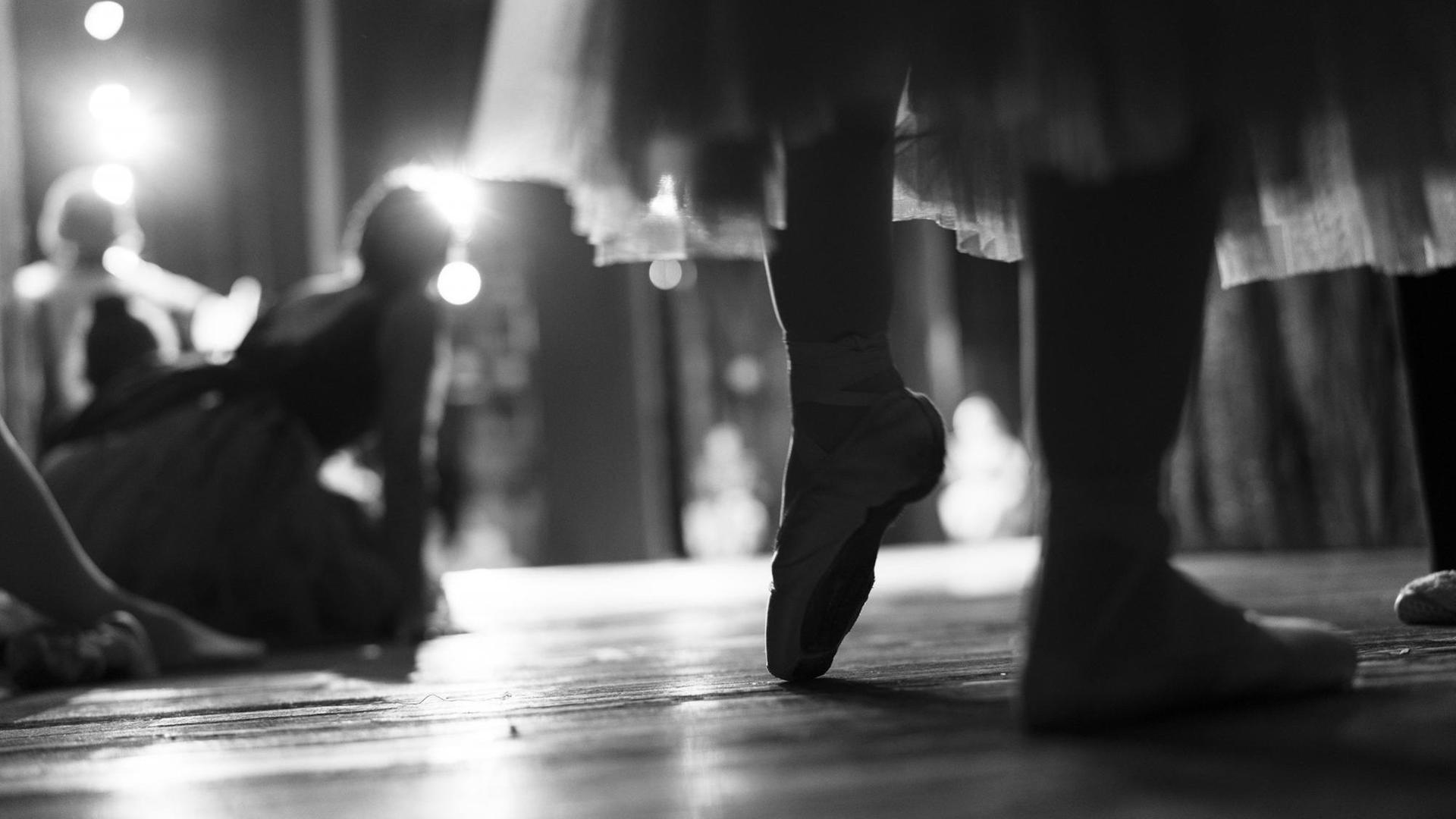 Die Schwarz-Weiß-Aufnahme zeigt Beine einer Frau mit Ballettschuhen. Die Schwarz-Weiß-Aufnahme zeigt Beine einer Frau mit Ballettschuhen.