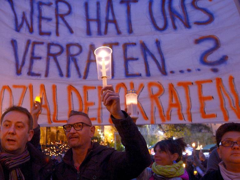 Teilnehmer einer Protestaktion gegen eine mögliche rot-rot-grüne Landesregierung in Thüringen halten auf dem Domplatz in Erfurt ein Banner mit der Aufschrift "Wer hat uns verraten...? Sozialdemokraten!" hoch.
