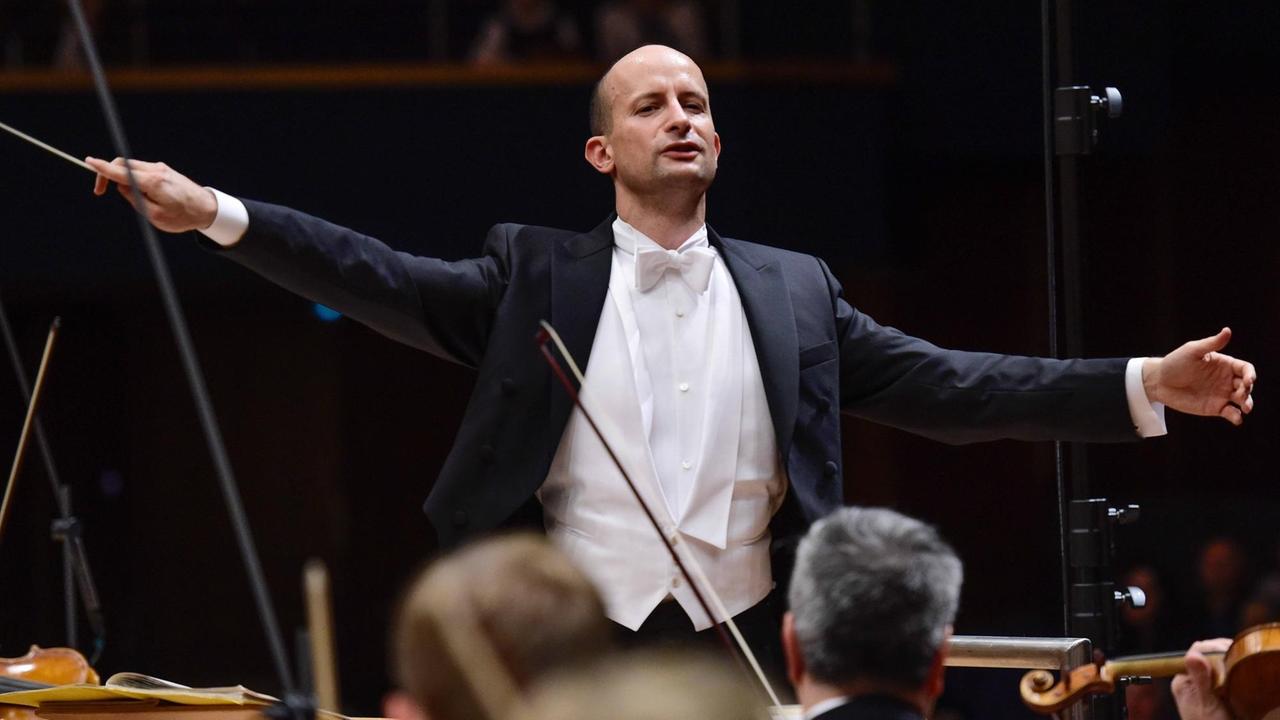 Der Dirigent bei seiner Arbeit in einem Konzert vor dem Orchester Der Dirigent bei seiner Arbeit in einem Konzert vor dem Orchester
