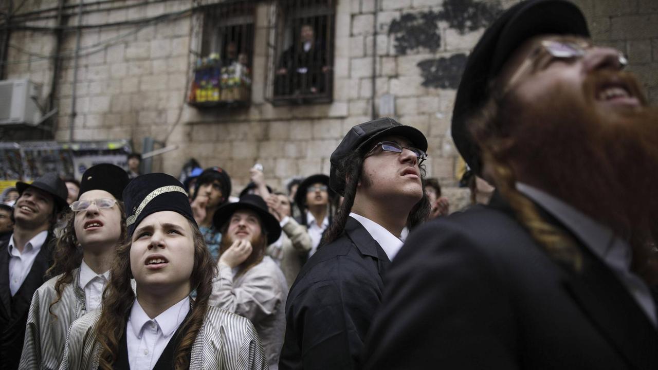 Ultraorthodoxe Juden im Viertel Mea She'arim in Jerusalem schauen während des Purimfestes am 13. März 2017 zu, als eine Soldatenpuppe im Zuge eines Protestes extremisitscher Ultraorthodoxer gegen den Wehrdienst von einem Gebäude hängt.