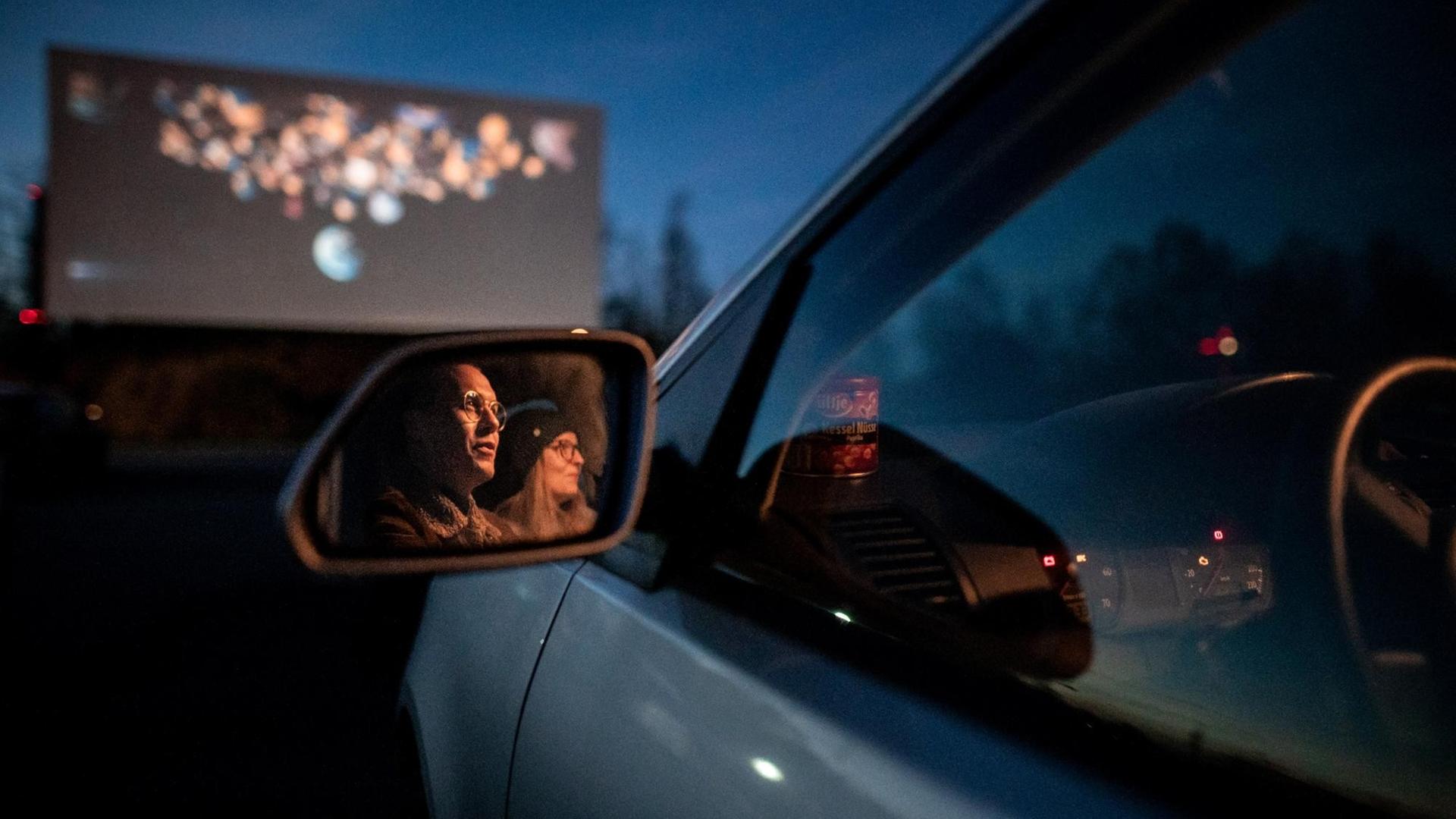 Zwei Besucher des Autokino sitzen im Auto und gucken auf die Leinwand. Das Kino in Essen hat auch während der Corona-Pandemie geöffnet. Zwei Besucher des Autokino sitzen im Auto und gucken auf die Leinwand. Das Kino in Essen hat auch während der Corona-Pandemie geöffnet.