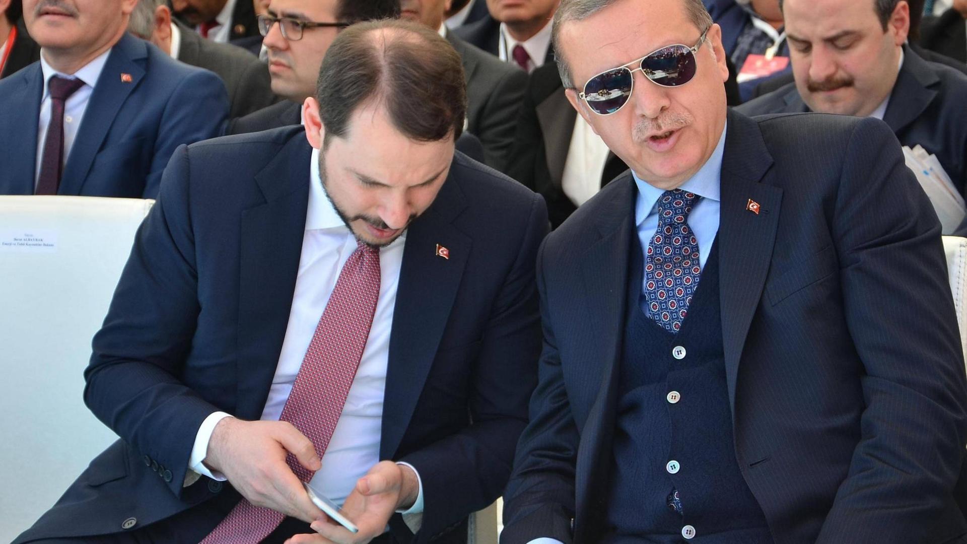 Der Türkische Staatspräsident Erdogan sitzt zusammen mit seinem Schwiegersohn Berat Albayrak bei einer Veranstaltung.