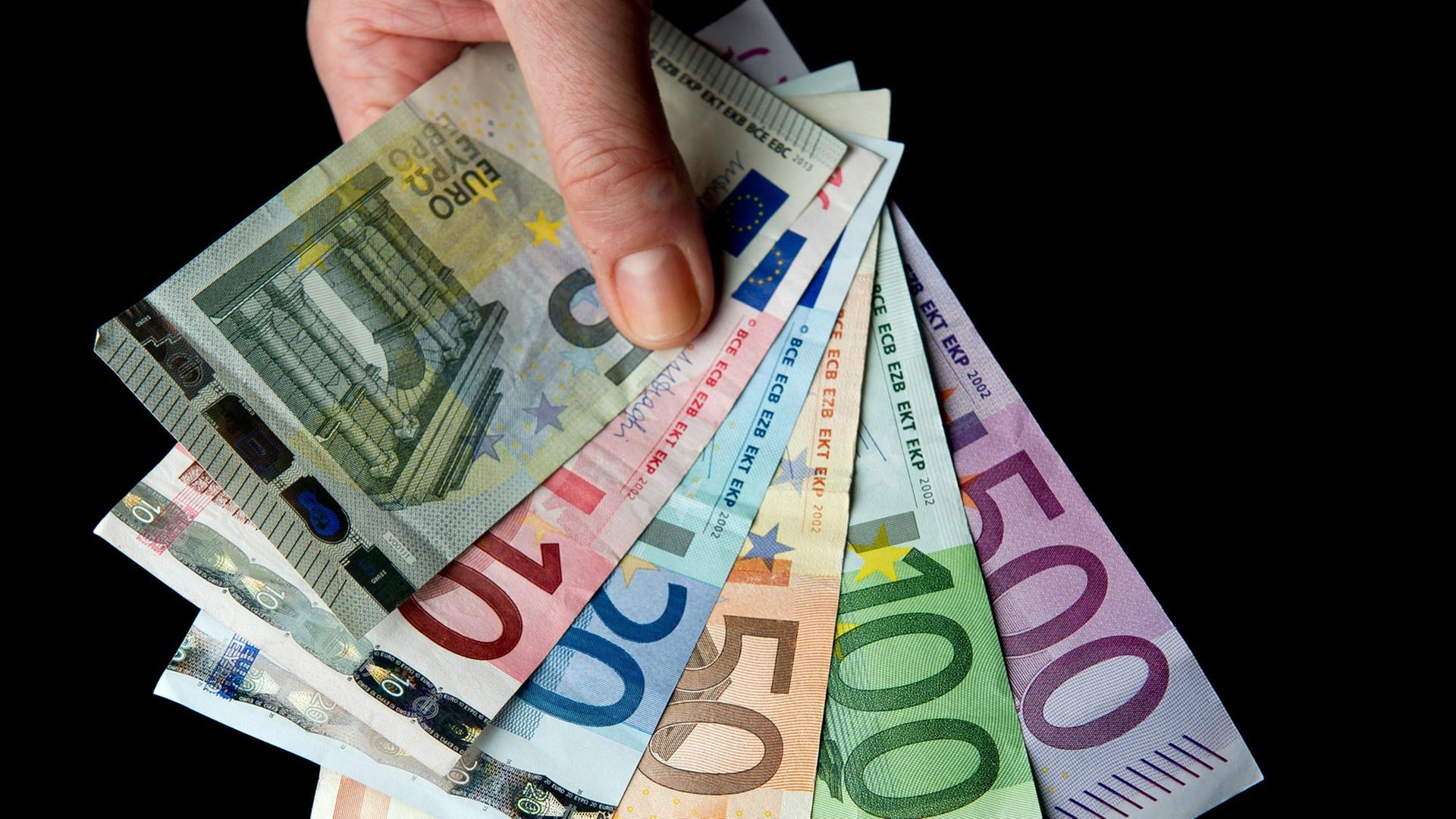 Eine Hand hält die sechs verschiedenen Banknoten zu 5, 10, 20, 50, 100 und 500 Euro.