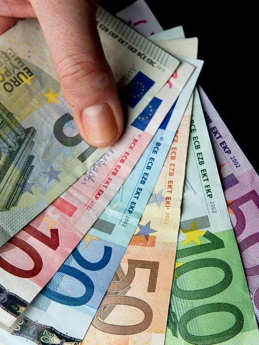 Eine Hand hält die sechs verschiedenen Banknoten zu 5, 10, 20, 50, 100 und 500 Euro.
