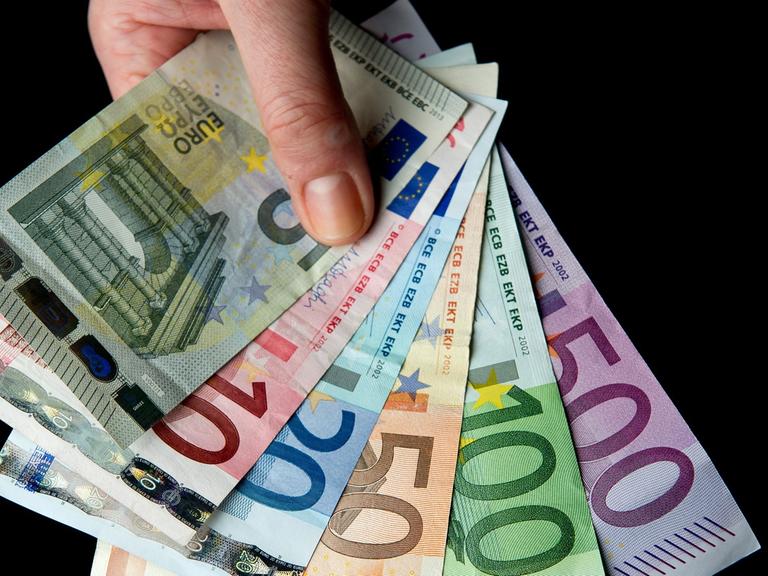 Eine Hand hält die sechs verschiedenen Banknoten zu 5, 10, 20, 50, 100 und 500 Euro.