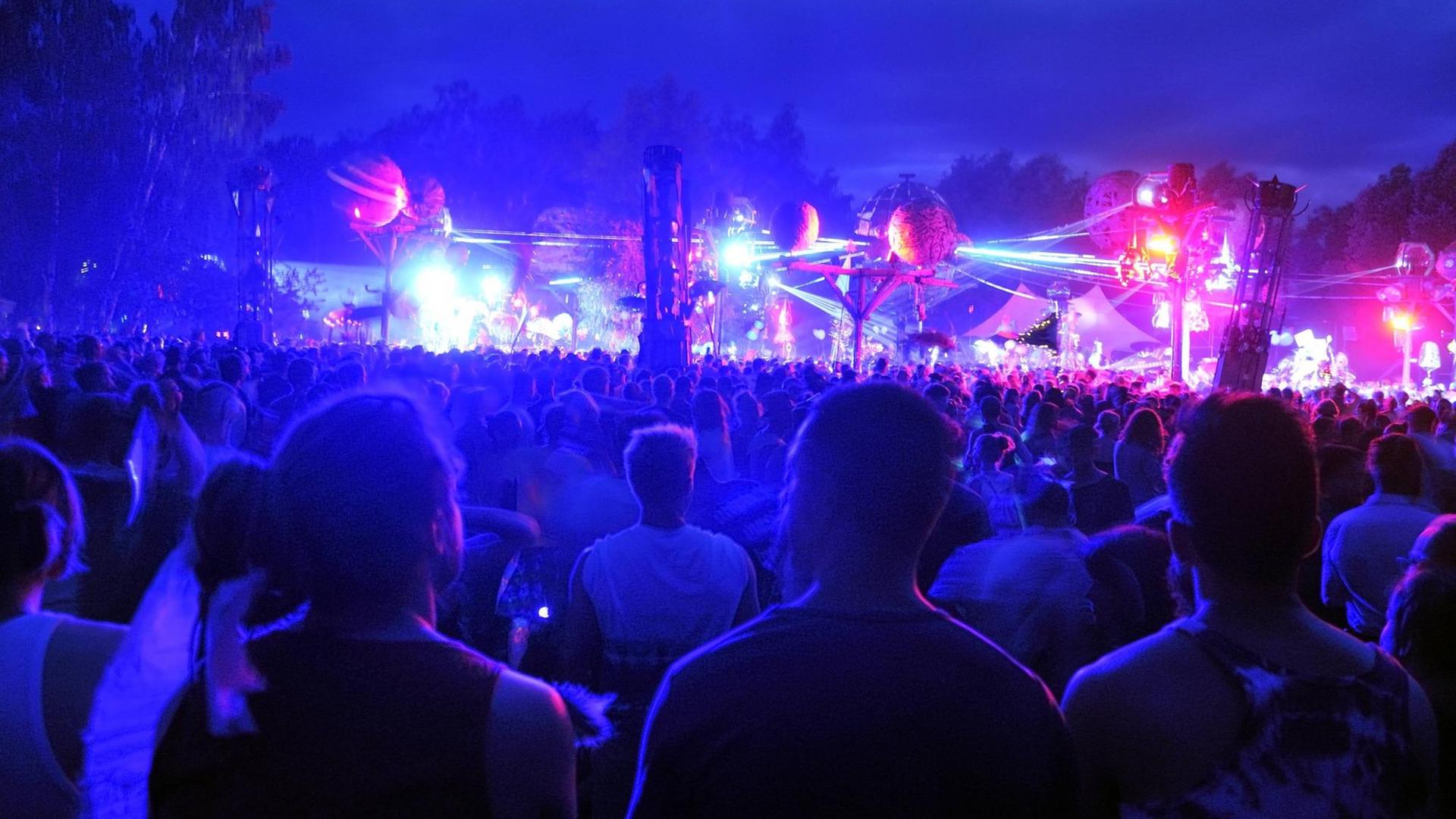 Besucher tanzen nachts auf dem bunt beleuchteten Gelände des Fusion-Festivals. Besucher tanzen nachts auf dem bunt beleuchteten Gelände des Fusion-Festivals.