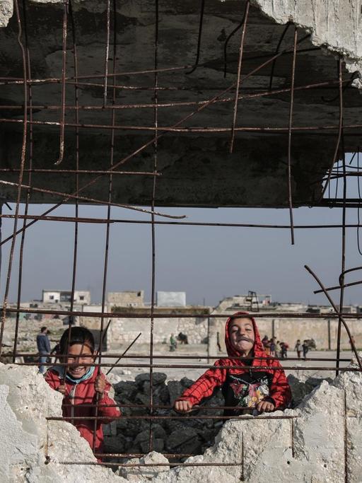 23.01.2019, Syrien, Jisr al-Shughur: Kinder spielen in den Trümmern der schwer beschädigten Al-Kefir-Schule. Mehr als 200 Schüler gehen hier immer noch zur Schule, obwohl Angriffe der syrischen Armee hier verheerende Spuren hinterlassen haben.