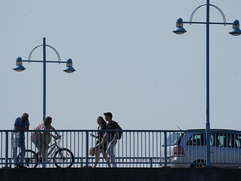 Blick auf eine Brücke die ein Auto und mehrere Fussgänger in beide Richtungen überqueren