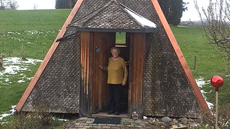 Eine ältere Frau steht in einer Holpyramide, die auf einem Feld steht. Eine ältere Frau steht in einer Holpyramide, die auf einem Feld steht.