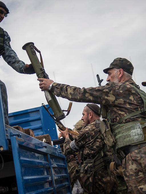 Pro-russische Aktivisten laden Waffen auf einen Truck, nachdem sie sich Gefechte mit ukrainischen Soldaten vor Donetsk geliefert haben.