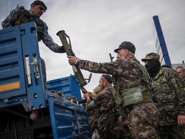 Pro-russische Aktivisten laden Waffen auf einen Truck, nachdem sie sich Gefechte mit ukrainischen Soldaten vor Donetsk geliefert haben.