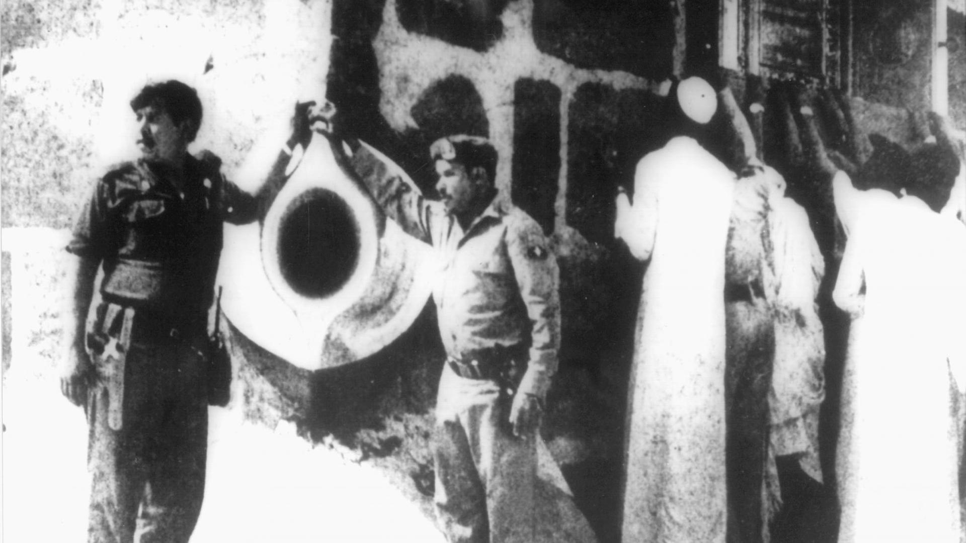 Pilger (r) küssen die Kaba, links Sicherheitskräfte, aufgenommen am 29. November 1979, während sich noch etliche Besatzer in den Kellergewölben verborgen halten. Am 20. November 1979 stürmen etwa 250 Anhänger einer islamischen Sekte die Haram-Mooschee in Mekka und nehmen mehrere hundert Gläubige als Geiseln. Drei Tage später stürmt die Nationalgarde Saudi-Arabiens das wichtigste Heiligtum der islamischen Welt. Etliche Besatzer sowie Soldaten kommen ums Leben, zahlreiche Geiselnehmer fliehen in die Katakomben der Moschee. Erst am 4. Dezember 1979 legt der letzte Aufrührer die Waffen nieder. Pilger (r) küssen die Kaba, links Sicherheitskräfte, aufgenommen am 29. November 1979, während sich noch etliche Besatzer in den Kellergewölben verborgen halten. Am 20. November 1979 stürmen etwa 250 Anhänger einer islamischen Sekte die Haram-Mooschee in Mekka und nehmen mehrere hundert Gläubige als Geiseln. Drei Tage später stürmt die Nationalgarde Saudi-Arabiens das wichtigste Heiligtum der islamischen Welt. Etliche Besatzer sowie Soldaten kommen ums Leben, zahlreiche Geiselnehmer fliehen in die Katakomben der Moschee. Erst am 4. Dezember 1979 legt der letzte Aufrührer die Waffen nieder.