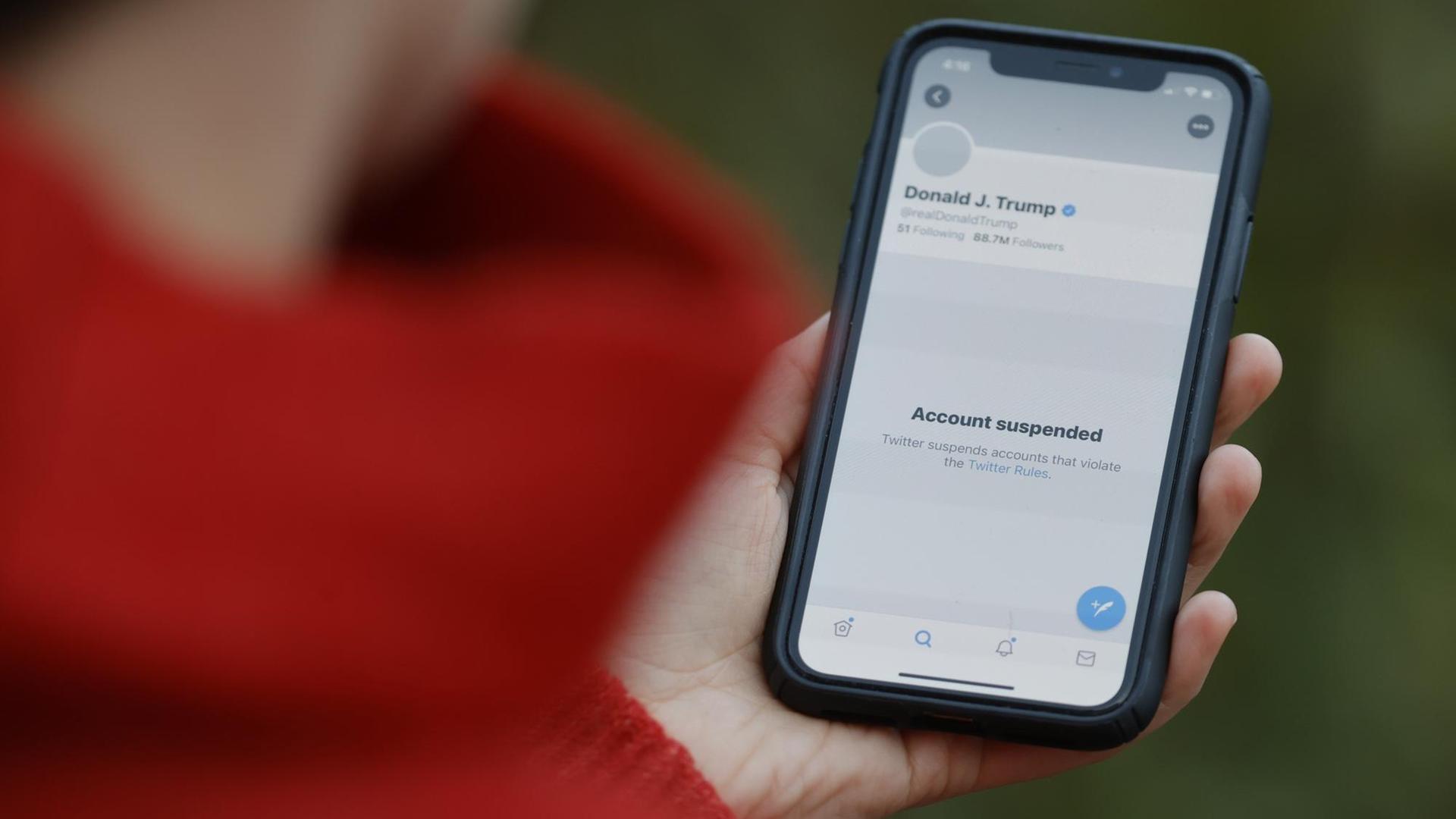 Person hält ein Smartphone in der Hand, das den suspendierten Twitter-Account von Donald Trump zeigt. Person hält ein Smartphone in der Hand, das den suspendierten Twitter-Account von Donald Trump zeigt.