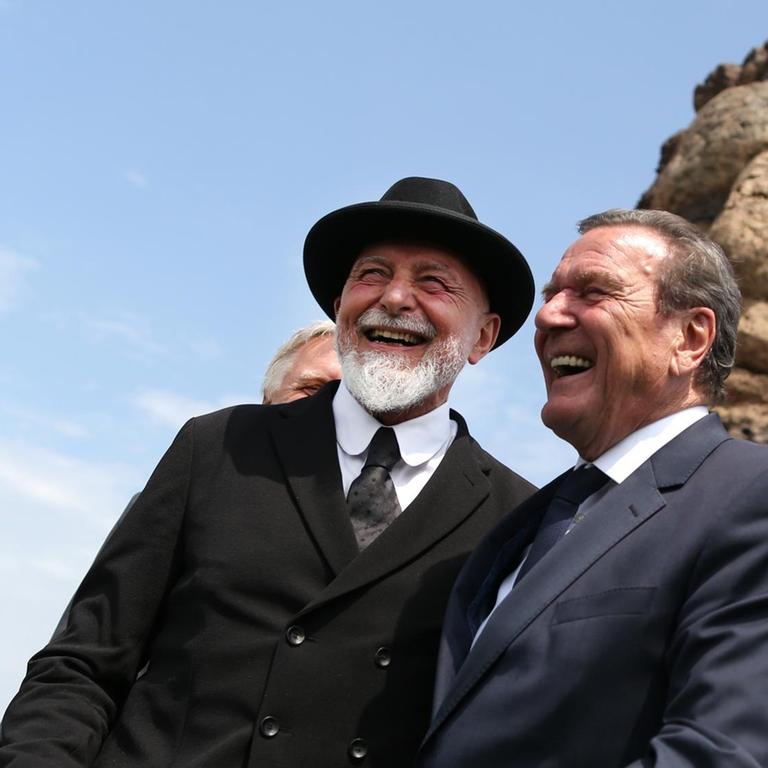Altbundeskanzler Gerhard Schröder (SPD, r) und Künstler Markus Lüpertz lachen am 27.05.2016 in Duisburg-Ruhrort (Nordrhein-Westfalen) bei der Enthüllung der Skulptur "Echo des Poseidon" auf der Mercatorinsel.
