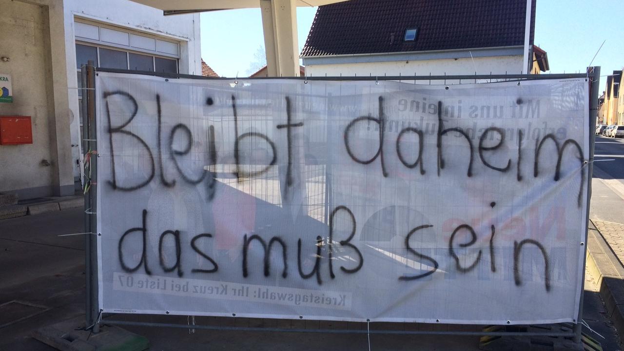 Großes weißes Transparent, besprüht mit schwarzen Buchstaben, Bleibt daheim das muss sein Großes weißes Transparent, besprüht mit schwarzen Buchstaben, Bleibt daheim das muss sein