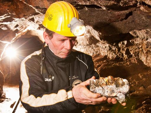 Ein Bergmann zeigt im einem Bergwerk im Erzgebirge einen Gesteinsbrocken mit Lithium.