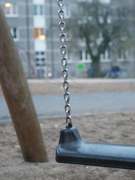 Eine Schaukel auf einem Spielplatz in Hamburg-Harburg - im Hintergrund geht ein Kind vorbei.