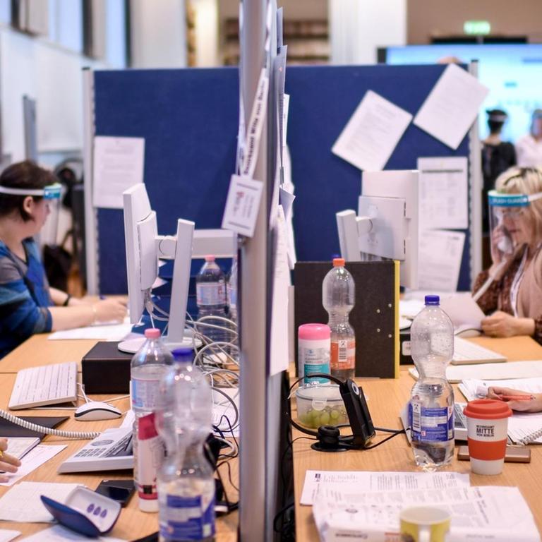 Mitarbeiter mit Gesichtsschutzschirm telefonieren im Lagezentrum des Gesundheitsamt Mitte. Das Gesundheitsamt Mitte führt eine neue Software-Lösung (Kontaktpersonen-Management-System SORMAS -Surveillance and Outbreak Response Management System) für die professionelle Verwaltung von Infektionsfällen ein