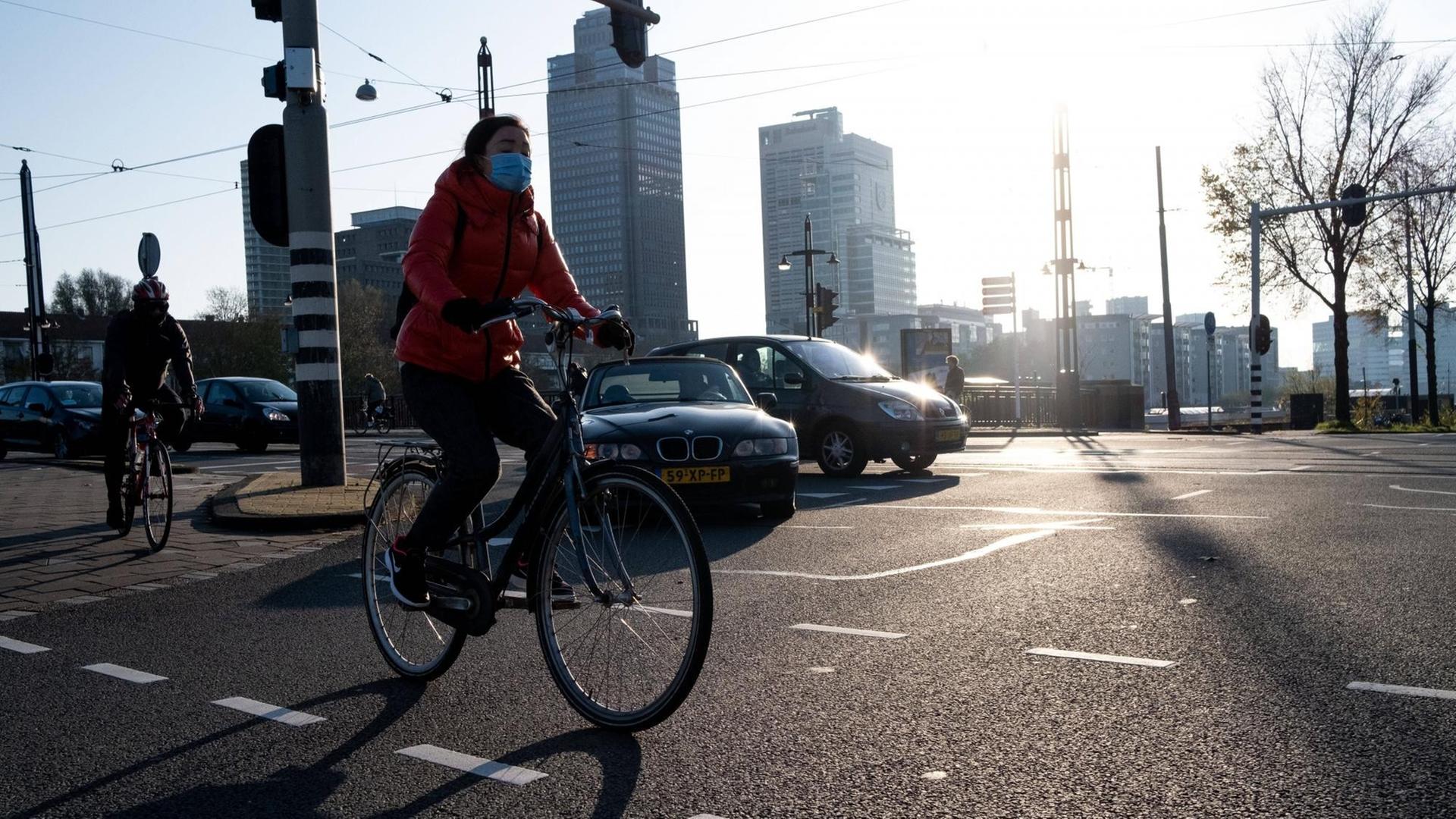 Eine Radfahrerin fährt mit Mund-Nasen-Bedeckung durch Amsterdam Eine Radfahrerin fährt mit Mund-Nasen-Bedeckung durch Amsterdam