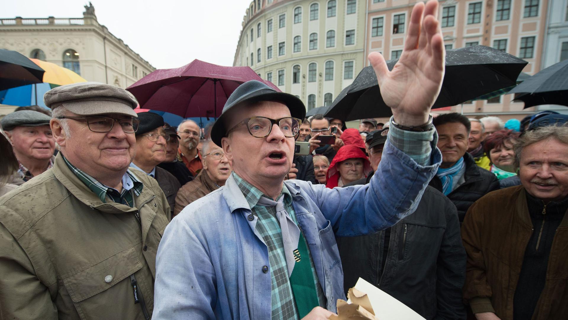 Der Dresdner Kabarettist Uwe Steimle steht am 08.05.2017 auf dem Neumarkt in Dresden (Sachsen). Steimle hatte zuvor ein hölzernes Modell des Dresdner Fernsehturms auf dem Neumarkt aufgestellt. Mit der Aktion möchte Steimle die Dresdner Bürger dazu bewegen, Kunstinstallationen statt mit Pöbeleien mit mehr Humor zu begegnen. Der etwa 70 Zentimeter hohe Fernsehturm mit einem Halbmond auf der Spitze soll außerdem dem Vorhaben zur Wiedereröffnung des Dresdner Fernsehturms neuen Anschub geben. Foto: Sebastian Kahnert/dpa-Zentralbild/dpa | Verwendung weltweit Der Dresdner Kabarettist Uwe Steimle steht am 08.05.2017 auf dem Neumarkt in Dresden (Sachsen). Steimle hatte zuvor ein hölzernes Modell des Dresdner Fernsehturms auf dem Neumarkt aufgestellt. Mit der Aktion möchte Steimle die Dresdner Bürger dazu bewegen, Kunstinstallationen statt mit Pöbeleien mit mehr Humor zu begegnen. Der etwa 70 Zentimeter hohe Fernsehturm mit einem Halbmond auf der Spitze soll außerdem dem Vorhaben zur Wiedereröffnung des Dresdner Fernsehturms neuen Anschub geben. Foto: Sebastian Kahnert/dpa-Zentralbild/dpa | Verwendung weltweit