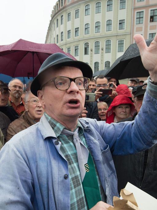 Der Dresdner Kabarettist Uwe Steimle steht am 08.05.2017 auf dem Neumarkt in Dresden (Sachsen). Steimle hatte zuvor ein hölzernes Modell des Dresdner Fernsehturms auf dem Neumarkt aufgestellt. Mit der Aktion möchte Steimle die Dresdner Bürger dazu bewegen, Kunstinstallationen statt mit Pöbeleien mit mehr Humor zu begegnen. Der etwa 70 Zentimeter hohe Fernsehturm mit einem Halbmond auf der Spitze soll außerdem dem Vorhaben zur Wiedereröffnung des Dresdner Fernsehturms neuen Anschub geben. Foto: Sebastian Kahnert/dpa-Zentralbild/dpa | Verwendung weltweit