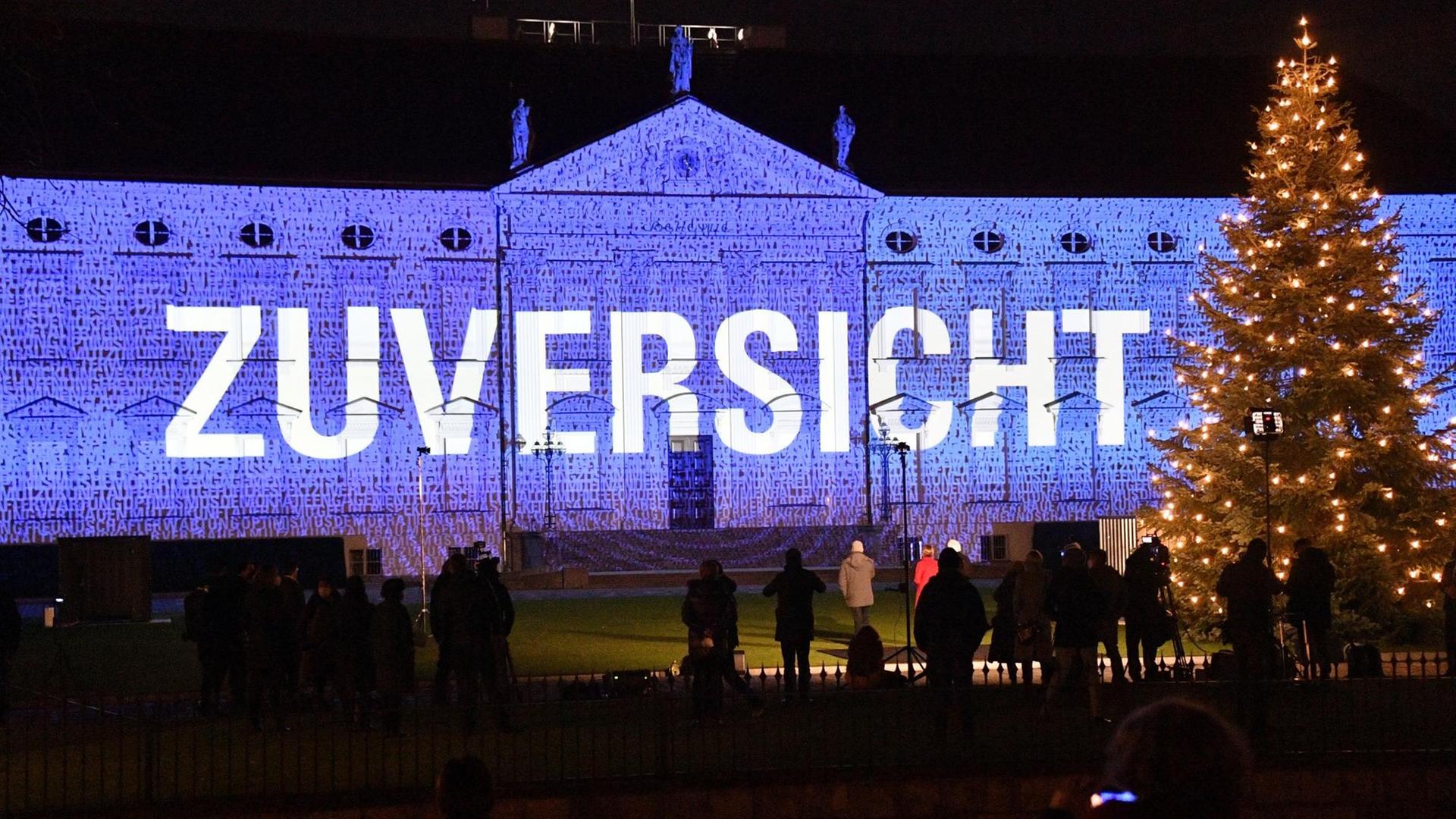 Im Rahmen der Lichtinstallation "Lichtblicke" ist auf das Schloss Bellevue in Berlin in Blau der Schriftzug "Zuversicht" projiziert. Davor steht bei einem Pressetermin unter anderen Bundespräsident Frank-Walter Steinmeier. Im Rahmen der Lichtinstallation "Lichtblicke" ist auf das Schloss Bellevue in Berlin in Blau der Schriftzug "Zuversicht" projiziert. Davor steht bei einem Pressetermin unter anderen Bundespräsident Frank-Walter Steinmeier.