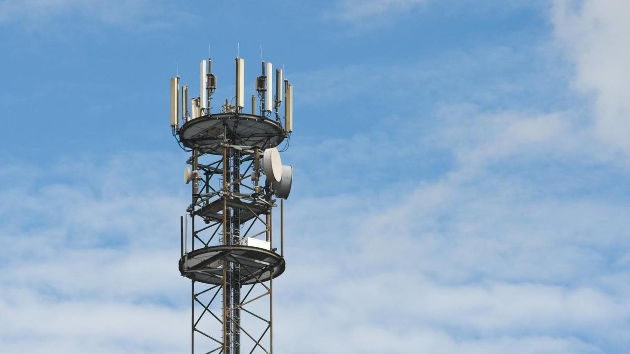 Ein Mobilfunkmast ist vor weiß-blauem Himmel zu sehen. Ein Mobilfunkmast ist vor weiß-blauem Himmel zu sehen.