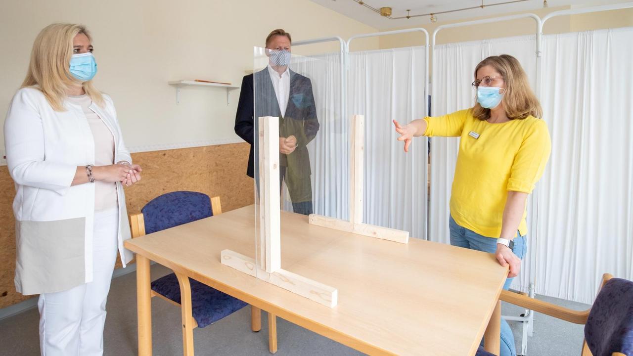 29.06.2020, Bayern, Lauf An Der Pegnitz: Kristine Lütke (r), Geschäftsführerin der Seniorenbetreuung und -pflege "bei St. Otto", erläutert Melanie Huml (CSU), Gesundheits- und Pflegeministerin aus Bayern, die Hygiene-Vorkehrungen im Besucherzimmer des Heims. Dahinter steht Norbert Dünkel (CSU), Mitglied des bayerischen Landtags. Die Ministerin informierte sich bei einem Besuch über die Umsetzung der neuen Besuchsregeln u.a. für Pflegeheime in Bayern. Foto: Daniel Karmann/dpa | Verwendung weltweit 29.06.2020, Bayern, Lauf An Der Pegnitz: Kristine Lütke (r), Geschäftsführerin der Seniorenbetreuung und -pflege "bei St. Otto", erläutert Melanie Huml (CSU), Gesundheits- und Pflegeministerin aus Bayern, die Hygiene-Vorkehrungen im Besucherzimmer des Heims. Dahinter steht Norbert Dünkel (CSU), Mitglied des bayerischen Landtags. Die Ministerin informierte sich bei einem Besuch über die Umsetzung der neuen Besuchsregeln u.a. für Pflegeheime in Bayern. Foto: Daniel Karmann/dpa | Verwendung weltweit