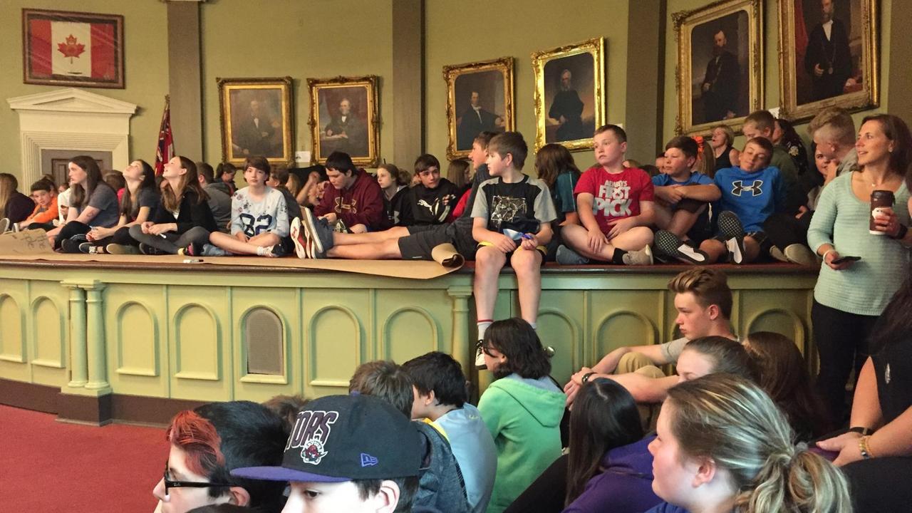 Schüler in Kanada sitzen am Boden und auf Tischen und hören zu. Schüler in Kanada sitzen am Boden und auf Tischen und hören zu.