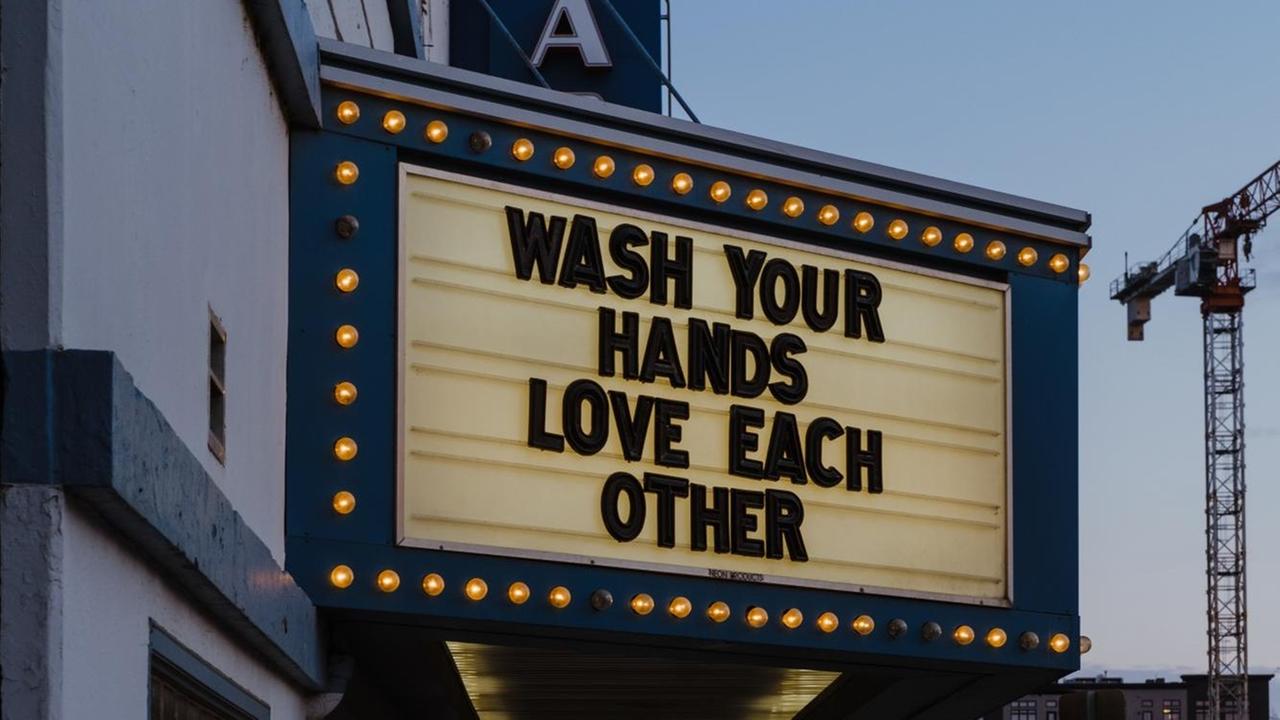 "Wash your hands. Love each other" steht als Schriftzug an einem Theatereingang. "Wash your hands. Love each other" steht als Schriftzug an einem Theatereingang.